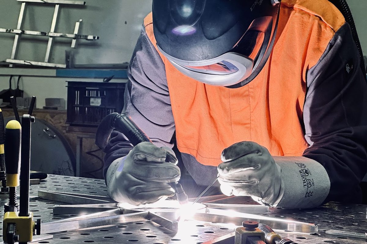 Svejser i beskyttelseshjelm svejser en lysstjernes metalkonstruktion